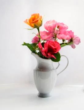White vase with colorful flowers on a light background Stock Photos
