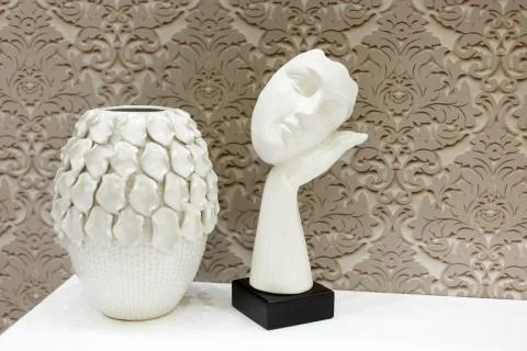 A white vase stands on the bedside table. A statue in the shape of a face in  Stock Photos