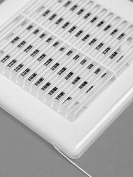 White ventilation grate on a gray background. Close-up. Material is plastic. Stock Photos
