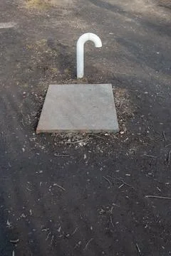 White ventilation pipe installed on a small metall base on the ground Stock Photos