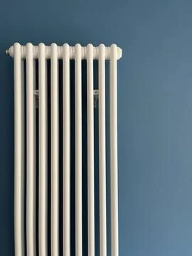White vertical heating system radiator on blue wall Stock Photos