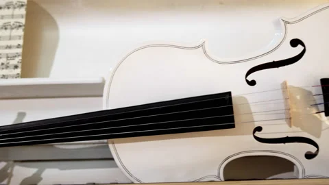 A white violin with a bow lies on a white piano 스톡 동영상 229690535
