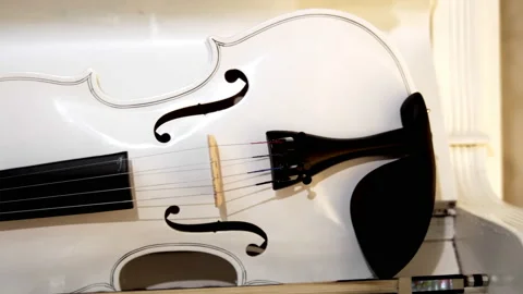 A white violin with a bow lies on a white piano Stock Footage 229690705
