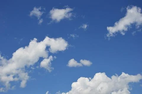 White voluminous clouds against a bright clear blue sky on a clear day. Stock Photos