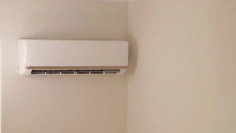 White wall air conditioner operating louvers in sunlit room Stock-Footage 346903329