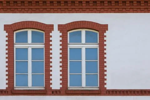 White wall of the building with two windows on the left side. The windows are Stock Photos