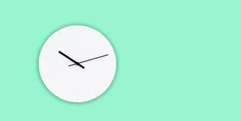 White wall clock with black clock hands hanging on the green mint wall. Minim Stock Photos