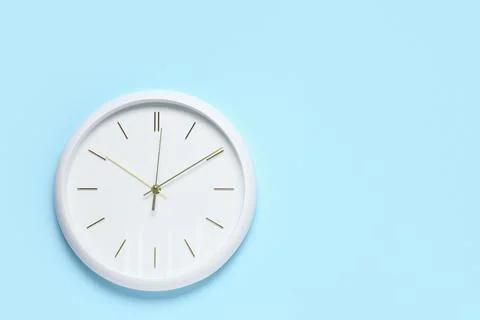 White wall clock on blue background showing time Stock Photos