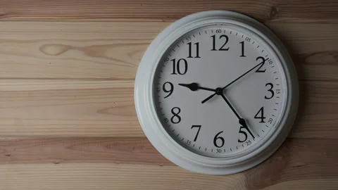 White wall clock hanging on textured wooden background 스톡 동영상 345432762