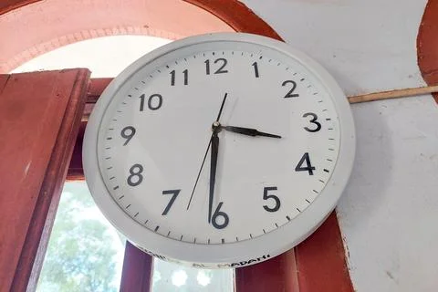 A white wall clock hangs on the wall in the room Stock Photos