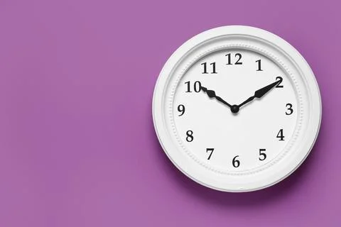 White wall clock showing time on purple background Stock Photos