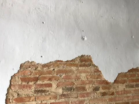 White wall with cracked space which shows red brown bricks inside Foto stock