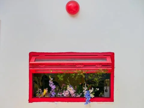 White wall with decorative red window and beautiful flowers and red ballons Stock Photos
