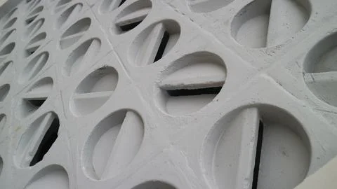 White wall with evenly spaced circular holes, geomteric pattern backgrounds Foto stock