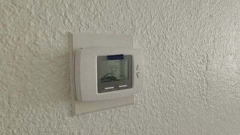 White wall mounted thermostat with triangular temperature control buttons Stock Footage 329656052