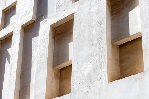 White wall with recessed windows creates an abstract pattern of light and shadow Stock Photos