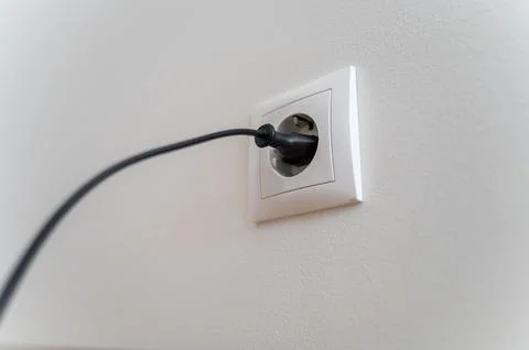 White wall socket with black plug and cable inserted Stock Photos