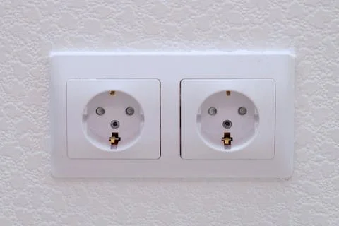 White wall socket with two outlets on a textured wall. Electrical power con.. Stock Photos