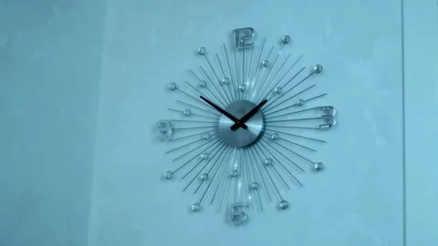 On the white wall there is a modern beautiful stylish chrome mechanical clock Stock Footage 297750508