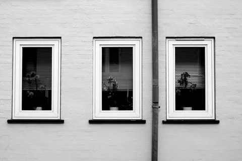 White wall with three windows half closed with jalousie in black and white Stock Photos