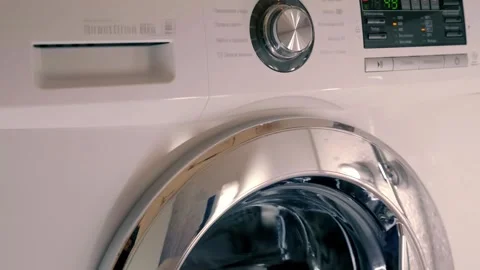 White washing machine with shiny chrome door washes clothes according to program Video stock 297755556