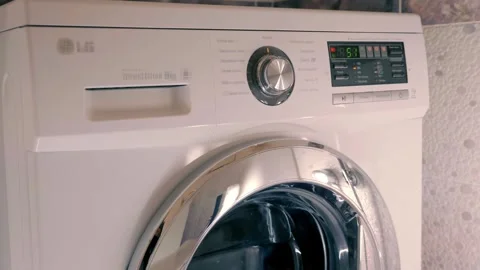 White washing machine with shiny chrome door washes clothes according to program Stock Footage 297809477