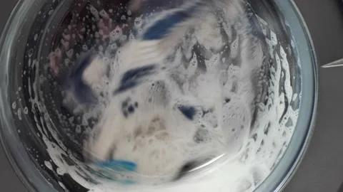 White washing machine washes dirty colorful clothes. Washing clothing in Stock Footage 213044288