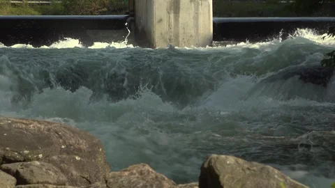 White water rapids flow under a sturdy stone bridge with a dam Stock Footage 325743805