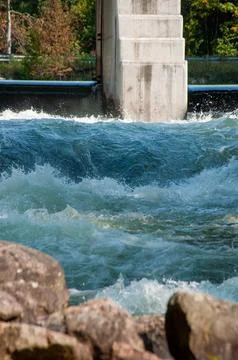 White water rapids flow under a sturdy cement bridge with a dam Stock Photos