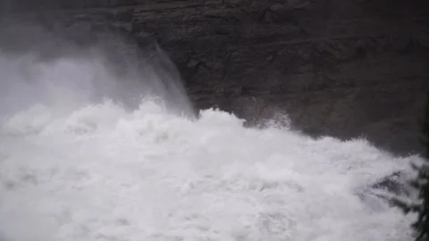 White water rapids rush by a cliff wall Video stock 92365567