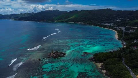 White Waves Breaking Over Reef Platform Near a Secluded Bay and Mountainous Stock Photos