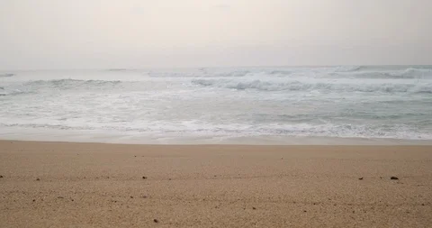 White waves breaking on sandy beach on cloudy day with fog on ocean Stock Footage 127136351
