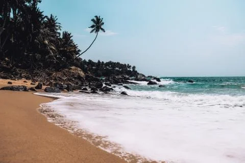 White waves breaking on smooth sand on a secluded beach in a remote island. Stock Photos