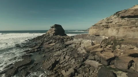 White waves crash against dark, rugged rocks Stock Footage 341822391