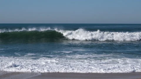 White waves forming on ocean and breaking on shore. Slow pan down. Stock Footage 168440985