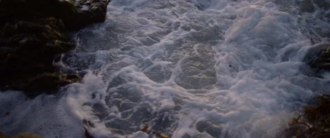 White waves rush into rocks in the evening light Video stock 136448870