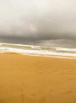 White waves on the sand beach with cloudy sky 库存照片