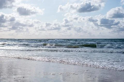 White waves of sea with clouds in the blue sky. The rolling sea on a cloudy d Stock Photos