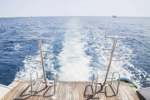 White waves from the ship engine and brown boards of the stern of ship Stock Photos