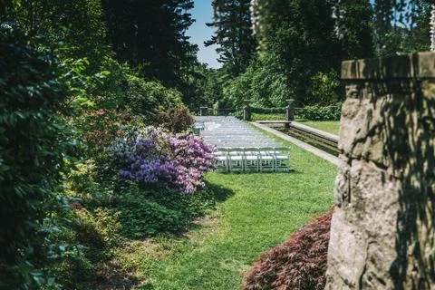 White Wedding Chairs Lined Up before a Real Life Outdoor Summer Wedding Ceremony Stock Photos