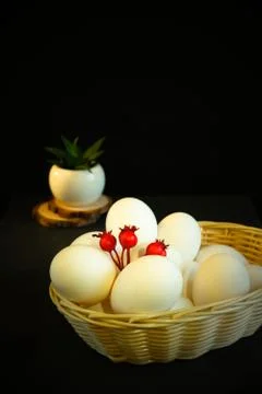 White wicker basket with easter eggs on a black background. Nearby lies a bru Stock Photos