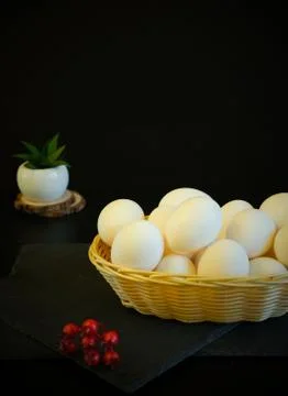 White wicker basket with easter eggs on a black background. Nearby lies a bru Stock Photos