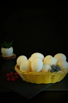White wicker basket with easter eggs on a black background. Nearby are severa Stock Photos