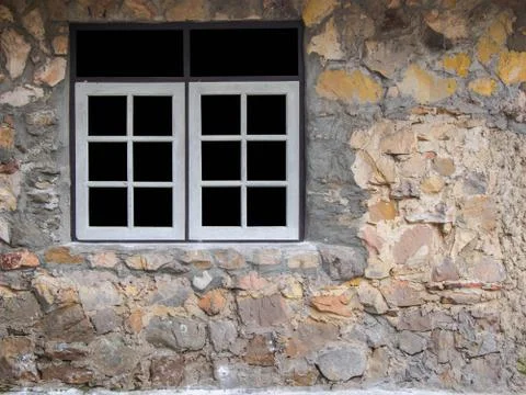 White window frame on the wall of a house made of stone. Stock Photos