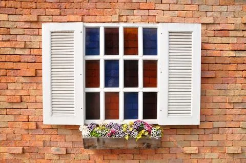 White window on red brick wall and color glass hang flowers pot. Stock Photos