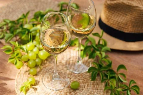 White wine and grapes on rustic table with leaves.. Stock Photos