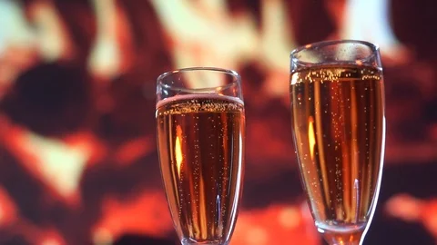 White wine being poured into on of two glasses in front of a fireplace. slow Stock Footage 100630704