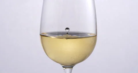 White wine drop falling with splashes in transparent glass in wine cellar Stock Footage 268469450