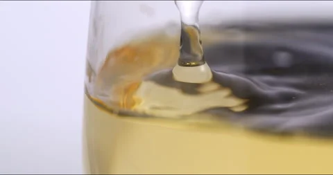 White wine drop falling with splashes in transparent glass in wine cellar Stock Footage 268476370