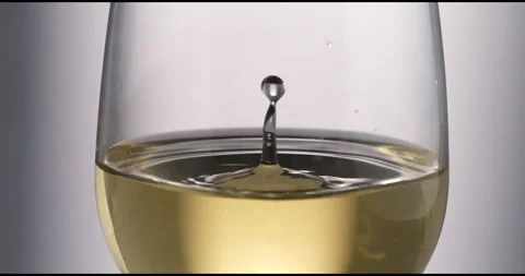 White wine drop falling with splashes in transparent glass in wine cellar Stock Footage 268476765
